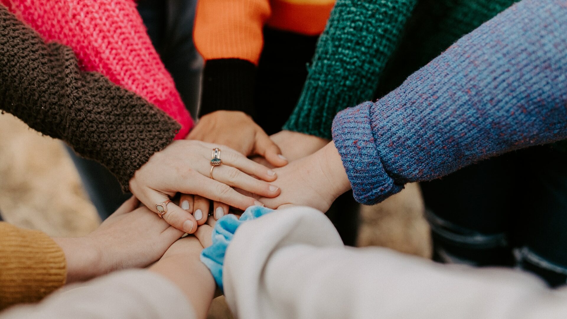 person in red sweater holding babys hand