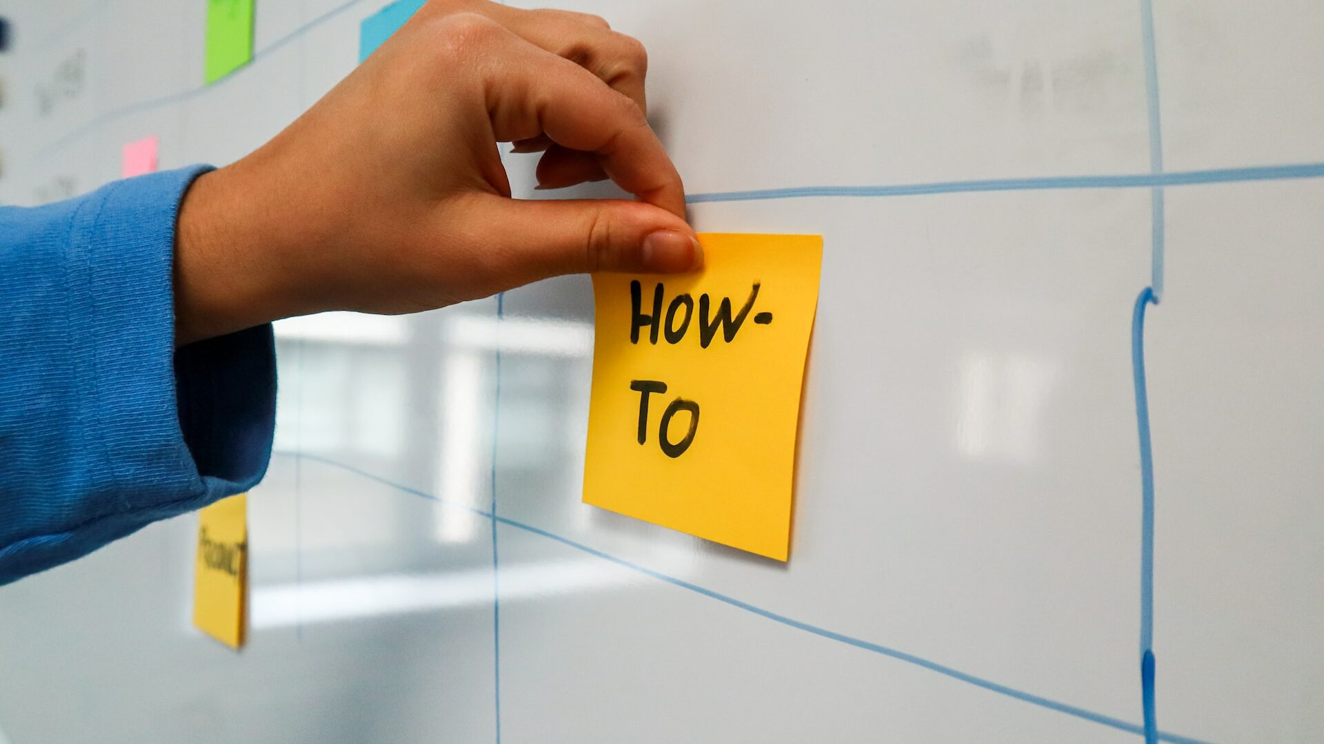 a sticky note pinned to a wall with the words how to written on it