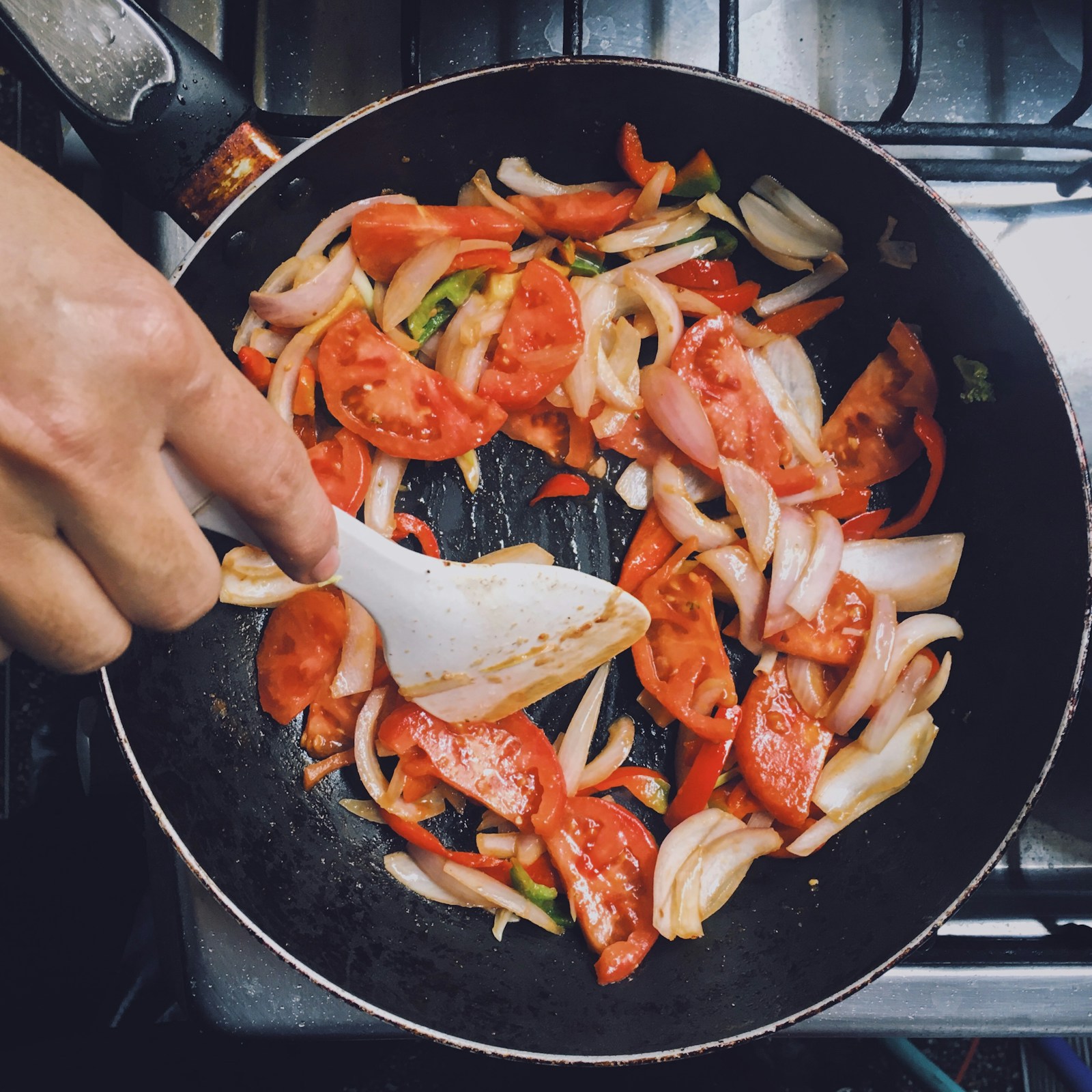 person holding black frying pan with cooked food