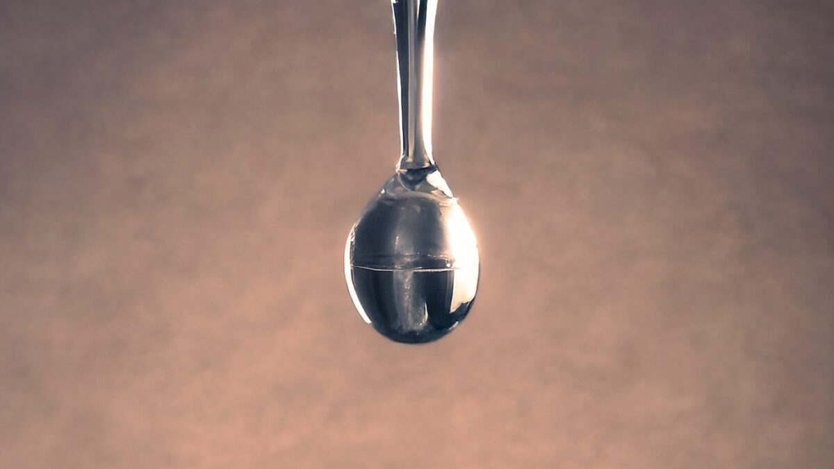 A water drop forms from a faucet.
