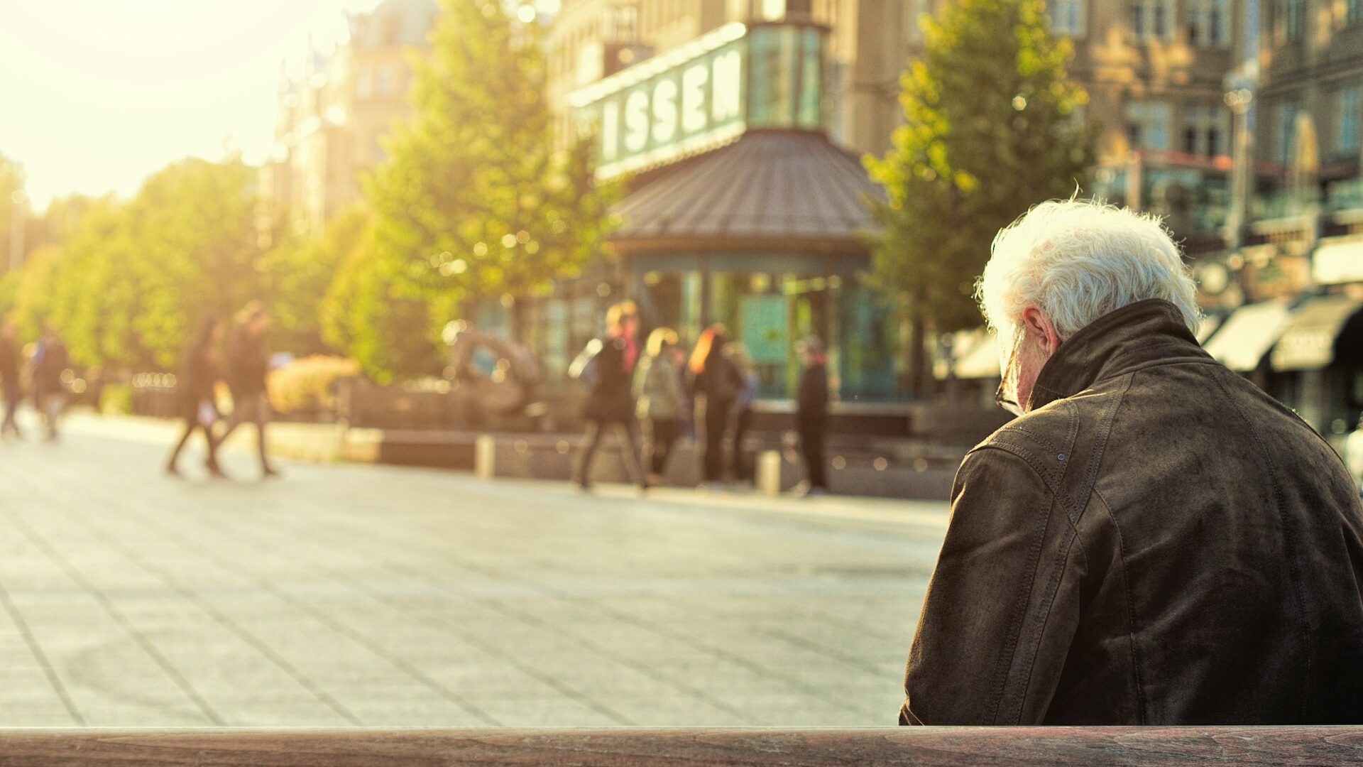 man sitting on brown wooden bench